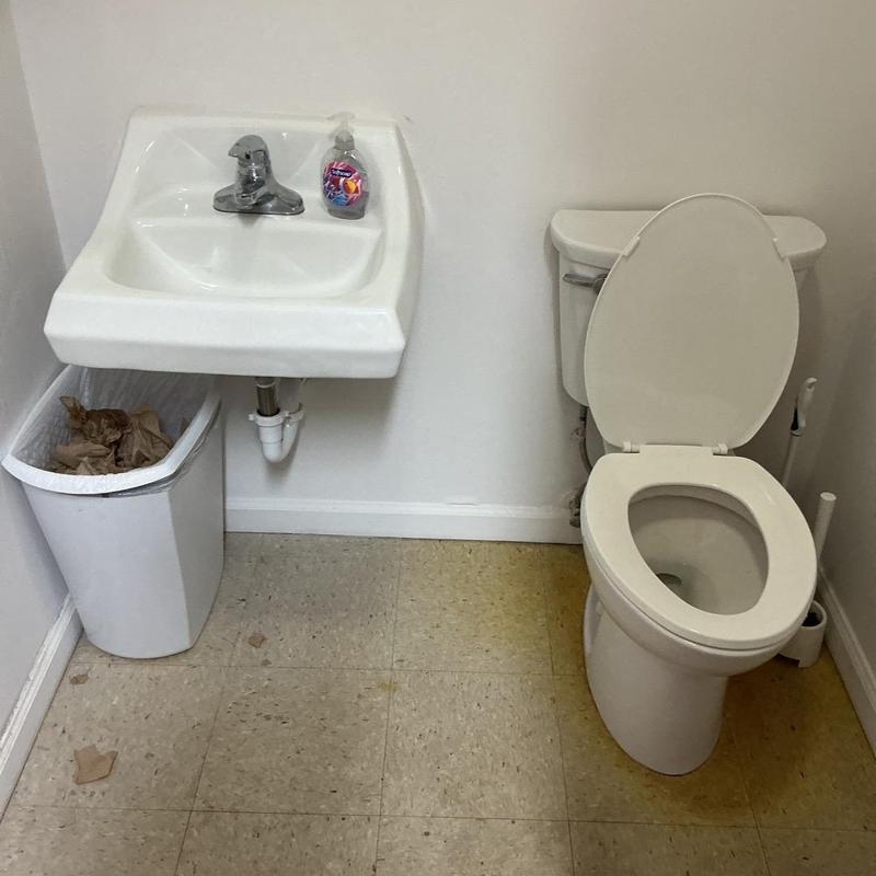 Toilet with open lid and wall-mounted sink in restroom Toilet with open lid and wall-mounted sink in restroom