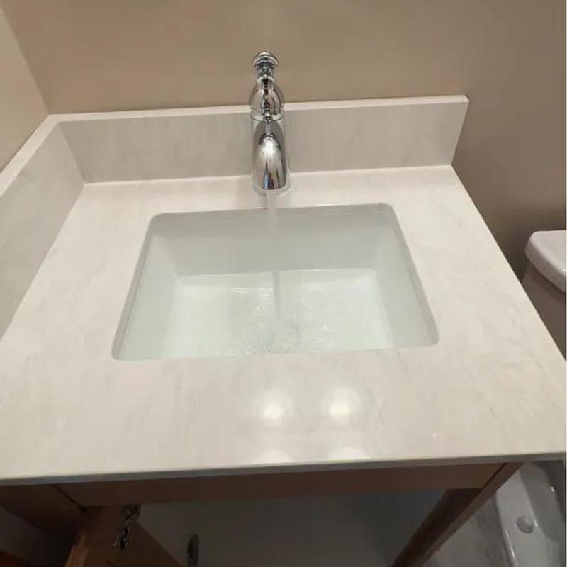 Bathroom sink faucet with running water and white countertop