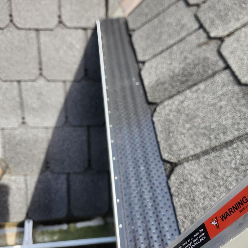 Gutter guard installation on shingle roof edge