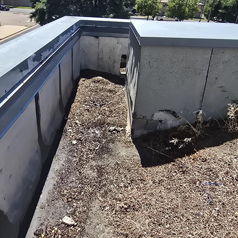 Modified bitumen roof with debris near scupper drains