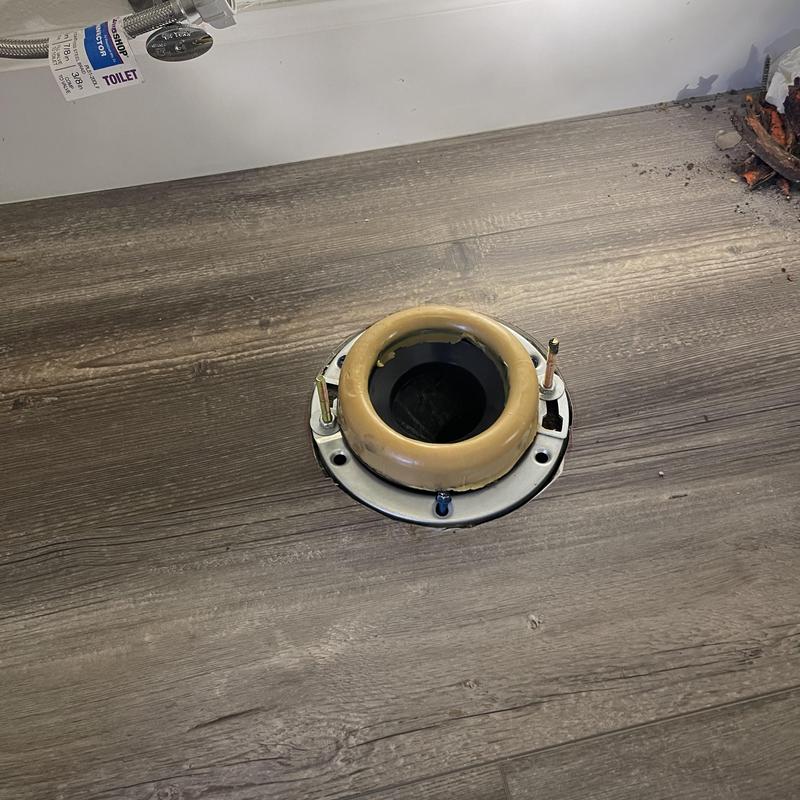 Toilet flange with new wax ring on wood floor
