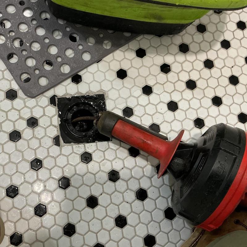 Drain snake clearing bathroom floor drain blockage