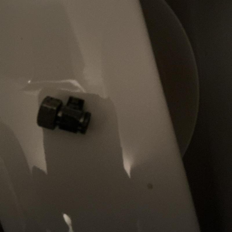 Toilet shut-off valve against white porcelain tank Toilet shut-off valve against white porcelain tank