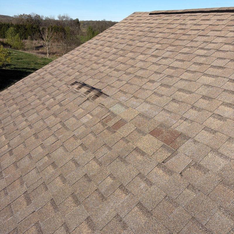 Asphalt roof shingles with hail damage and lifted section