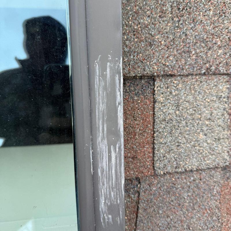 Window frame with paint scratches near shingle roof