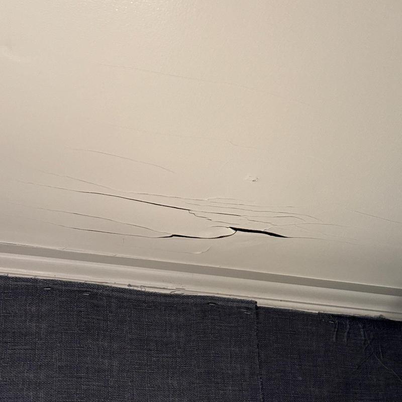 Ceiling drywall with peeling and cracks near wall trim