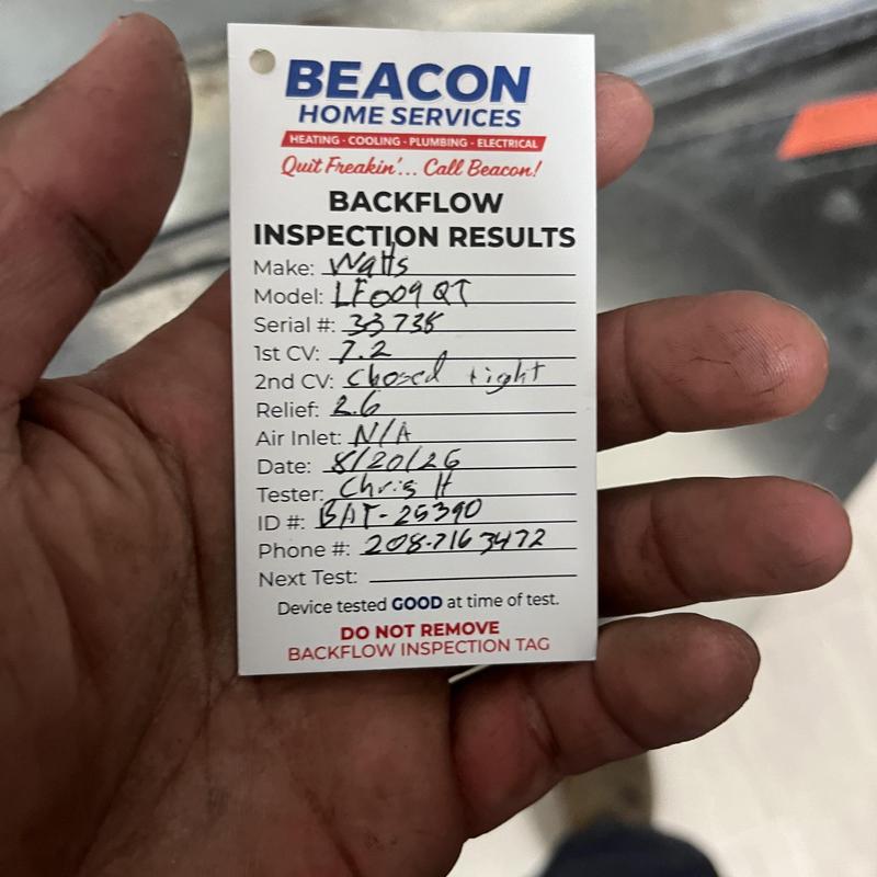 Backflow inspection results tag held in hand Backflow inspection results tag held in hand