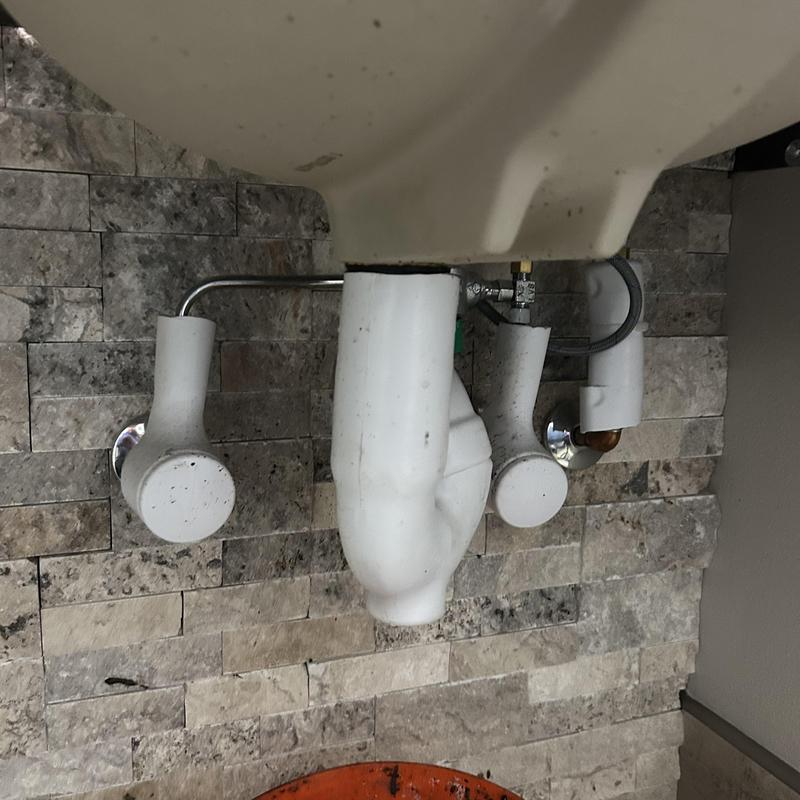 Bathroom sink drain pipes below countertop in stone tile wall Bathroom sink drain pipes below countertop in stone tile wall