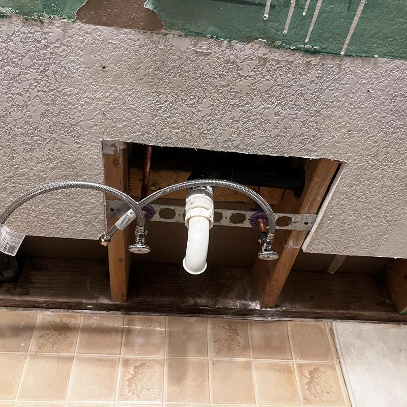 Sink drain and supply lines exposed behind drywall cutout Sink drain and supply lines exposed behind drywall cutout