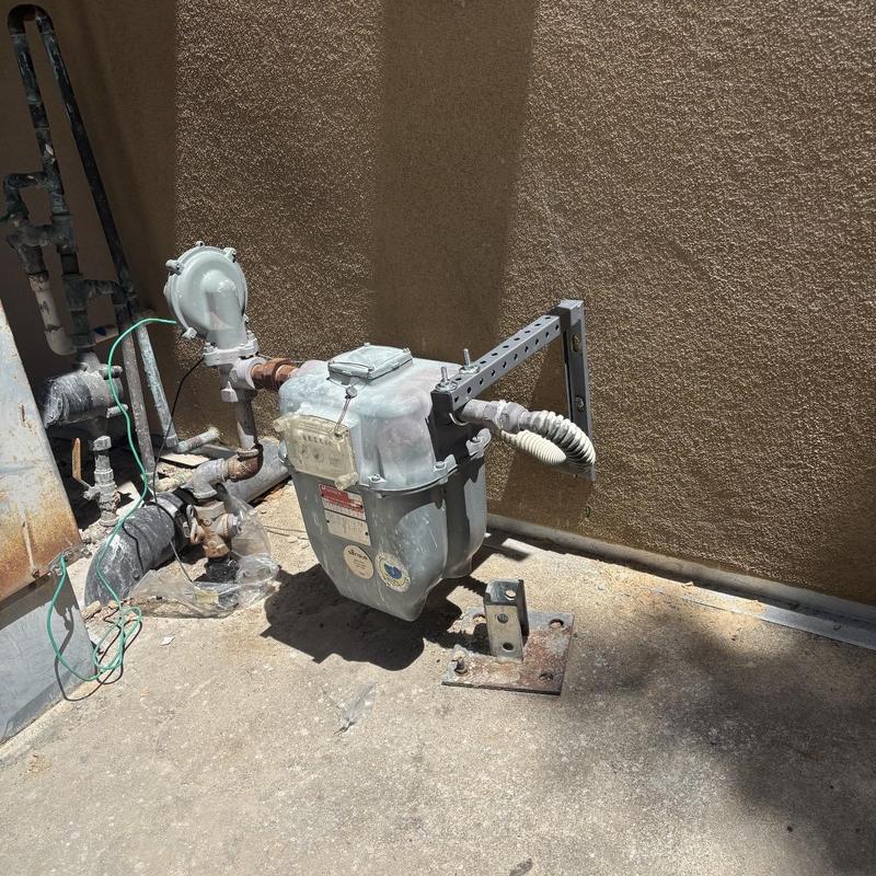 Gas meter support bracket installation on stucco wall