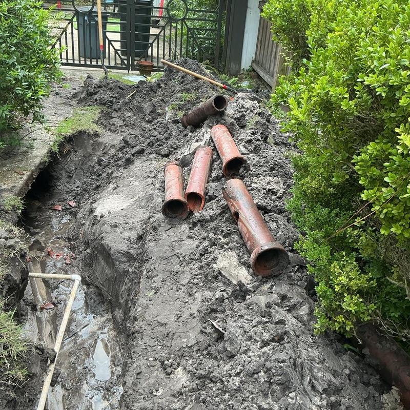 Clay sewer pipes removed from trench in muddy yard Clay sewer pipes removed from trench in muddy yard