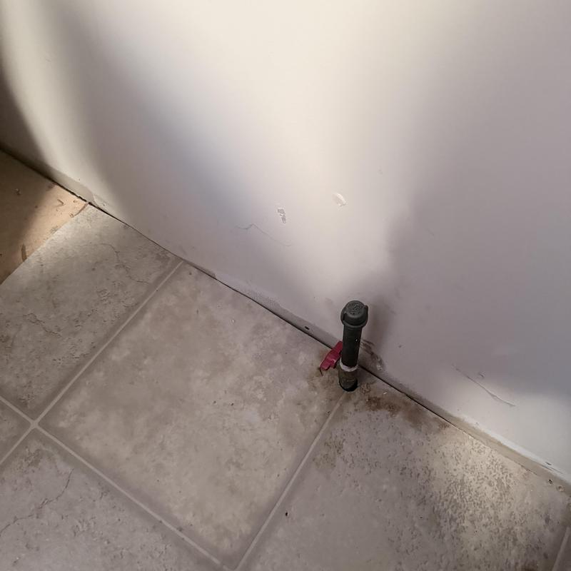 Emergency shut-off valve on tiled floor near wall Emergency shut-off valve on tiled floor near wall