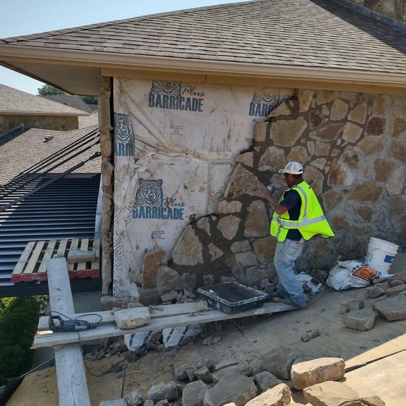 Stonewall exterior repair with worker applying mortar