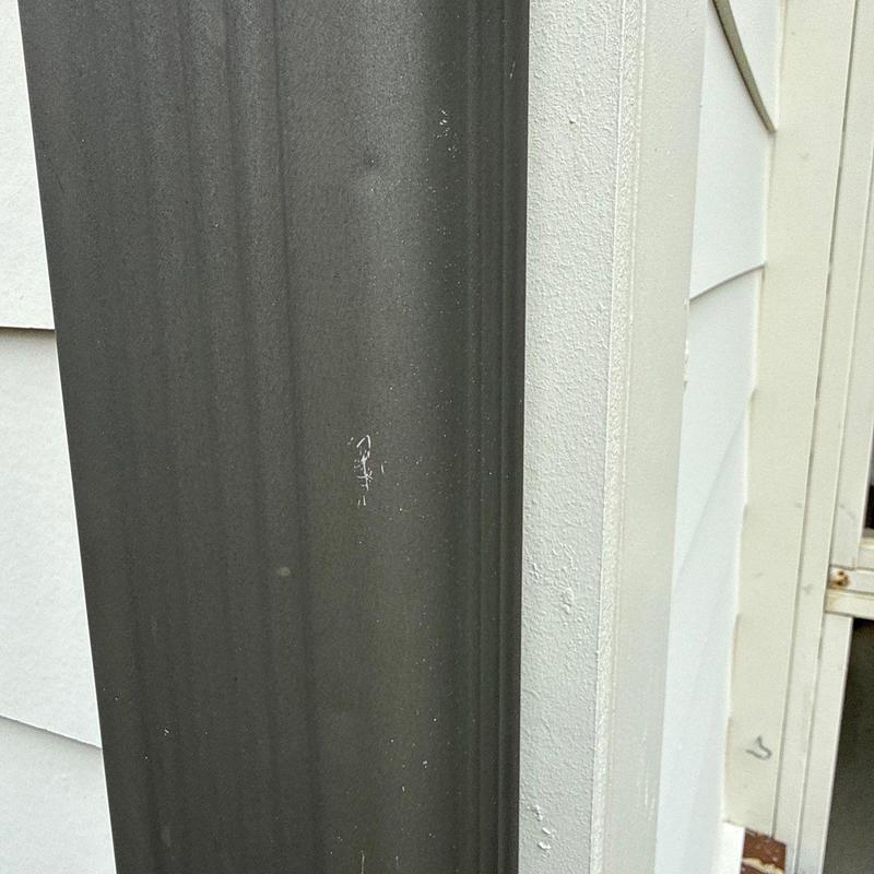 Downspout with minor surface scratches on exterior wall