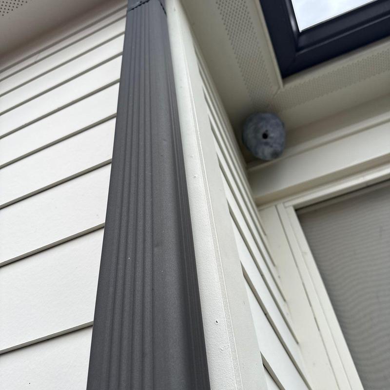 Downspout and house siding installation near window trim
