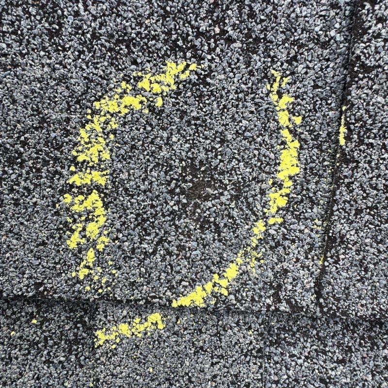 Asphalt shingle with hail damage marked in yellow
