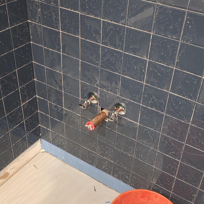 Flush valve plumbing installation with tiled wall