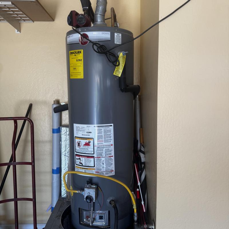 Gas water heater installation with safety labels visible