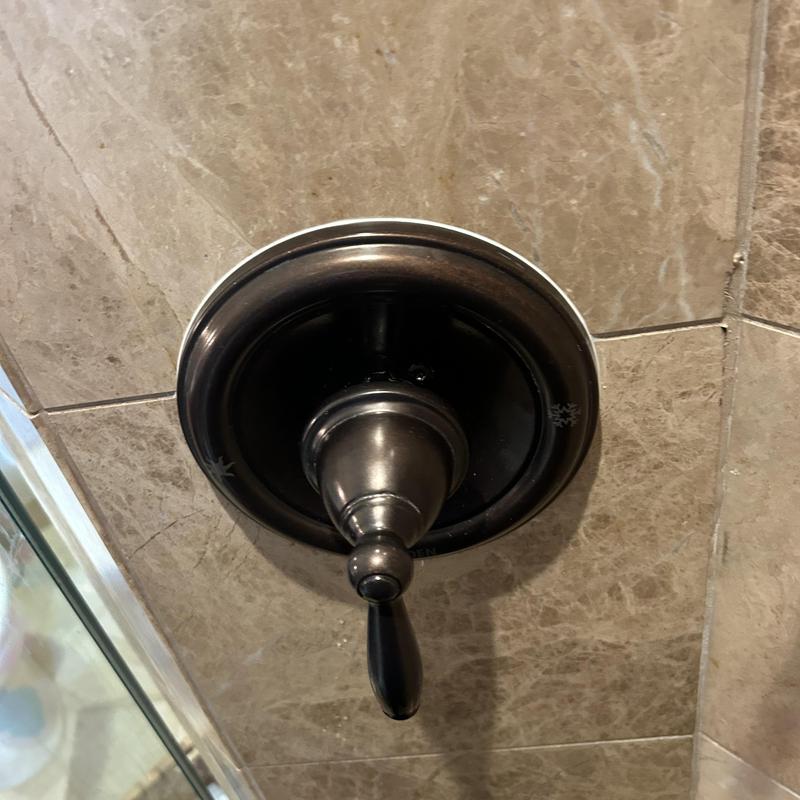 Shower valve handle on beige tile wall Shower valve handle on beige tile wall