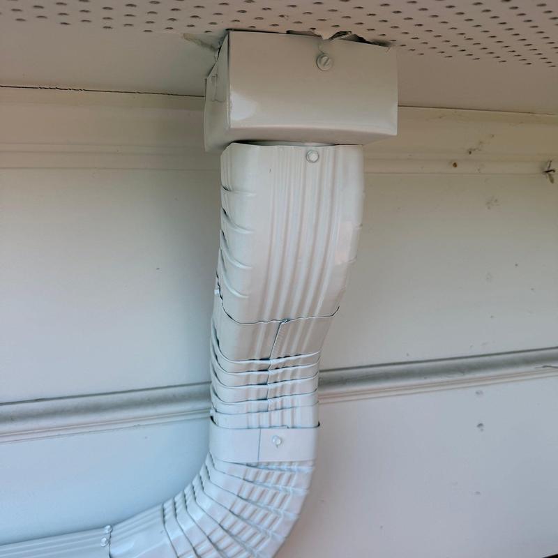 Downspout with bent and crushed sections near ceiling joint