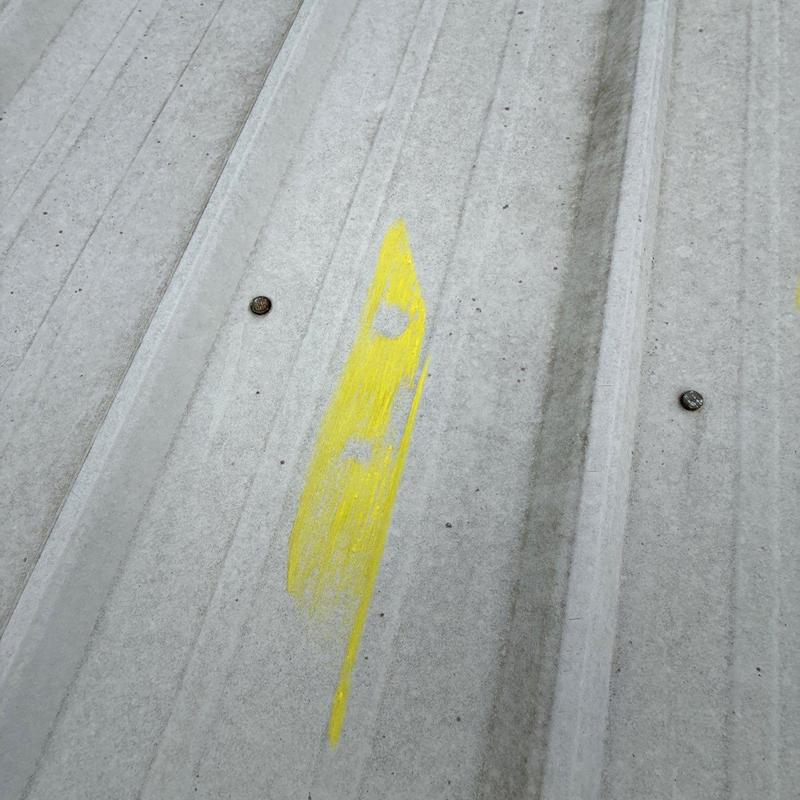 Metal roofing panel with hail damage marked in yellow