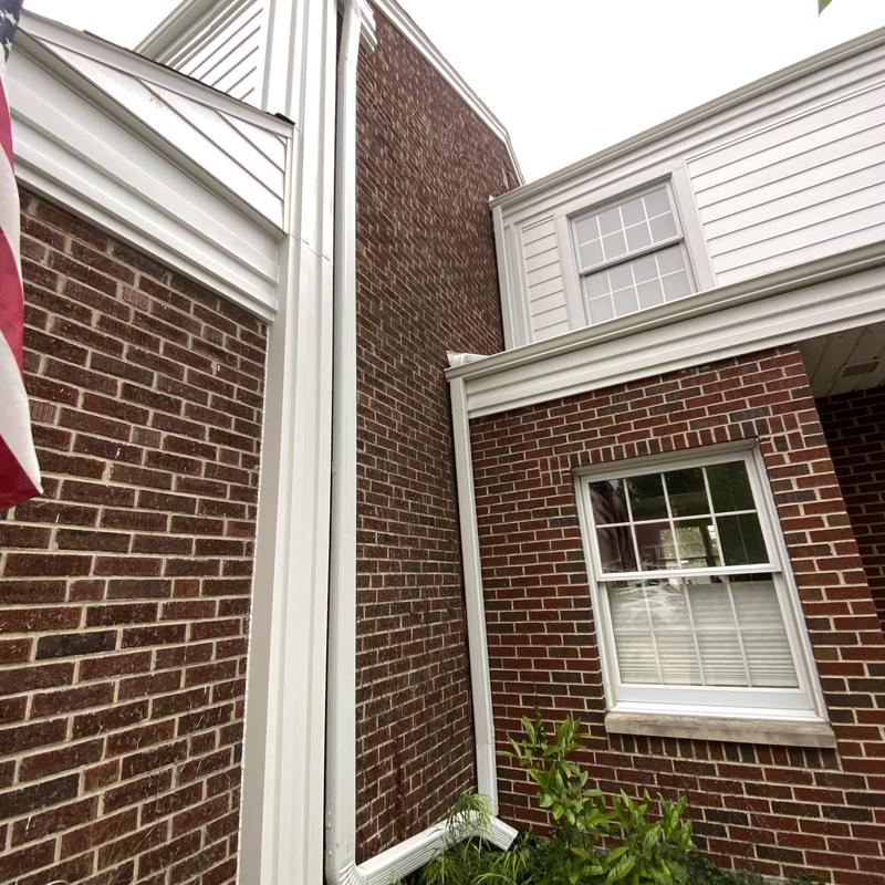 Composite insulated siding and white gutters on brick wall
