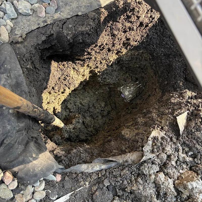 Sump pump discharge area with backfilled soil and shovel