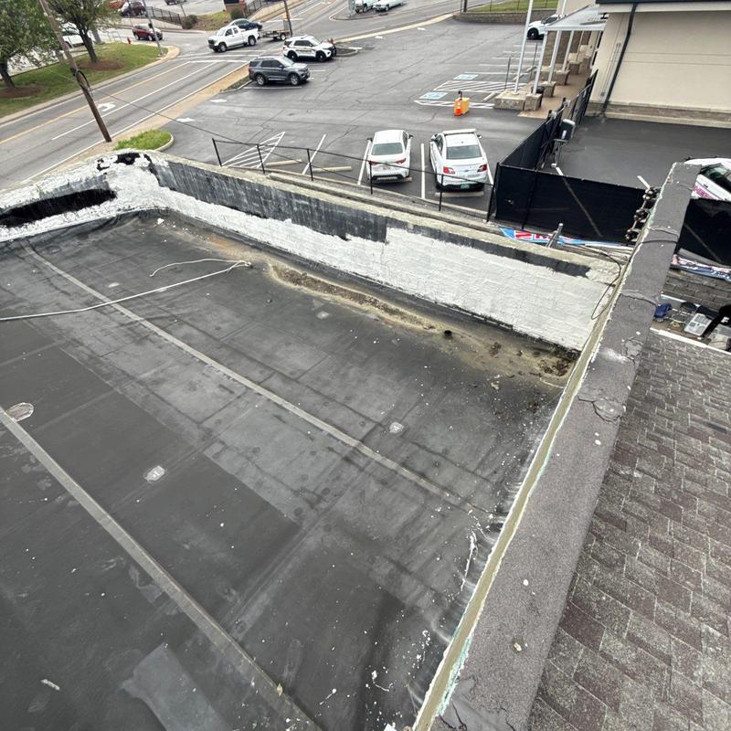 Flat commercial roof with hail damage near wall edge