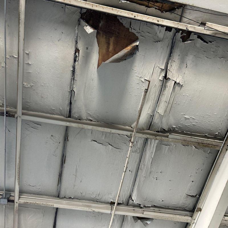 Commercial metal roof with hail damage and peeling paint