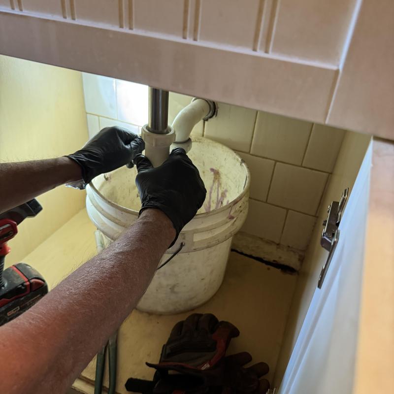 Lavatory sink drain with plumber's hands unclogging Lavatory sink drain with plumber's hands unclogging