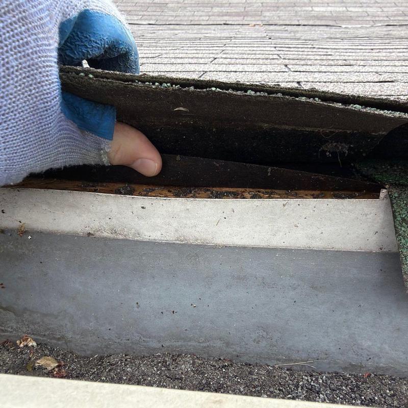 Roof shingles lifted for inspection above metal flashing