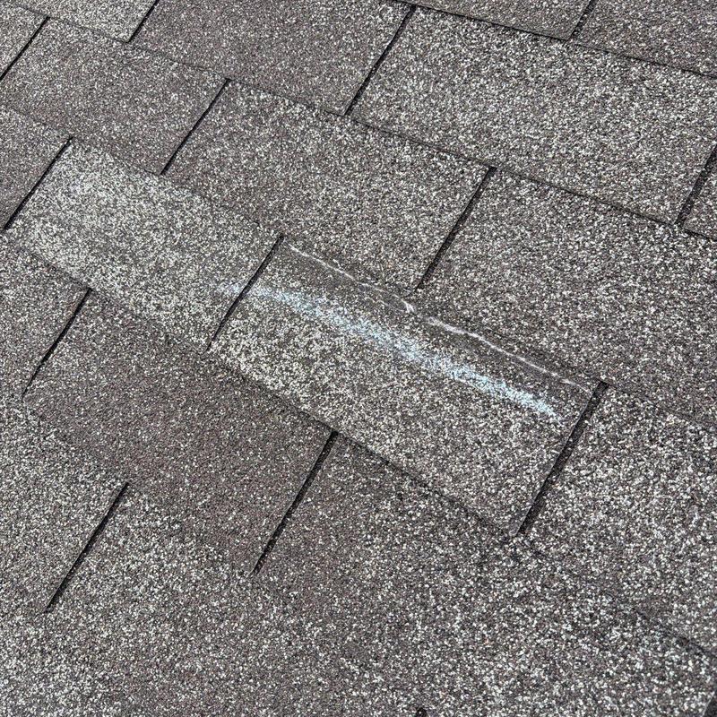 Asphalt roofing shingles with visible hail damage