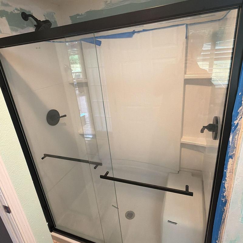 Glass sliding shower door with black Delta valves