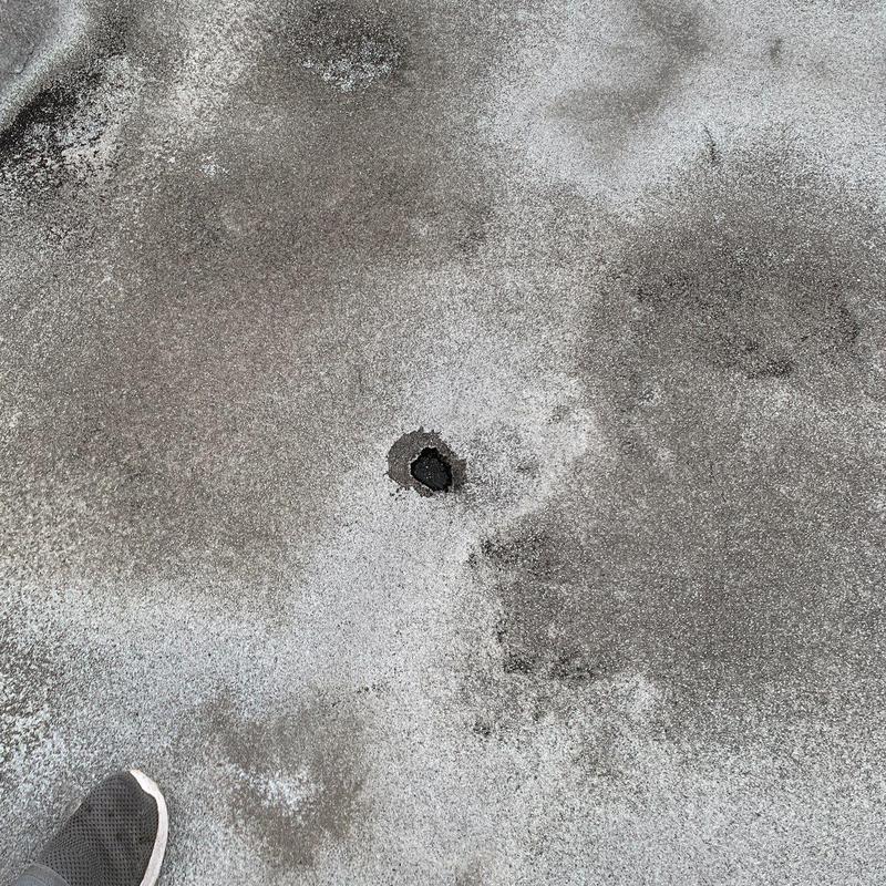 Commercial roof hail damage hole in membrane surface