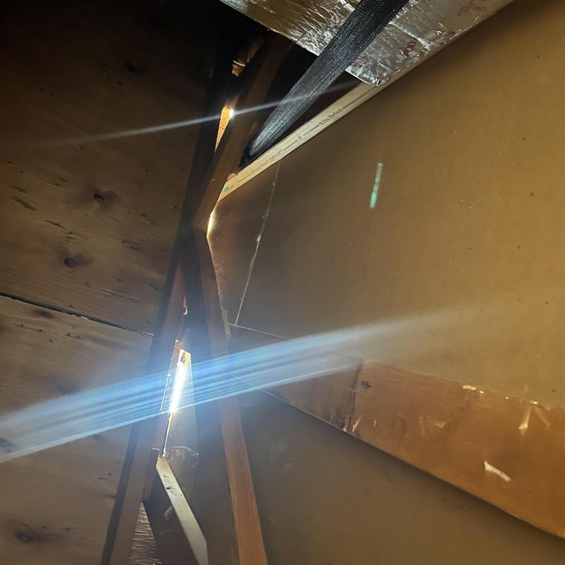 Attic scuttle with visible light leak and missing stucco