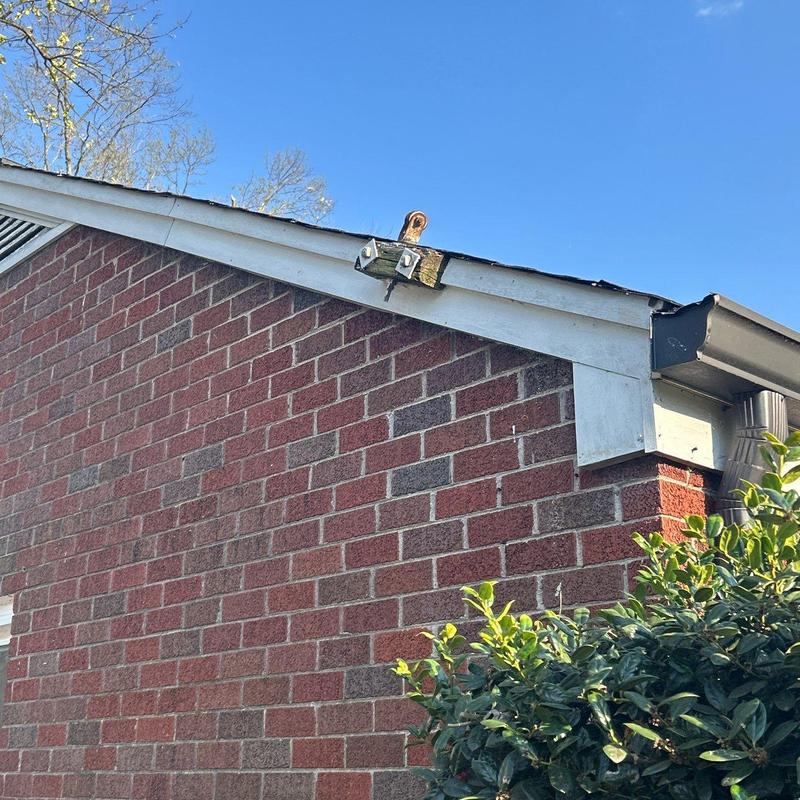 Roof shingles with hail damage on brick house edge
