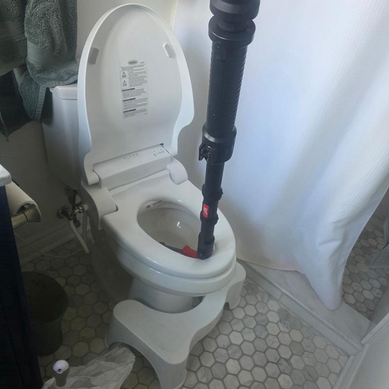 Toilet drain with auger cleaning in bathroom