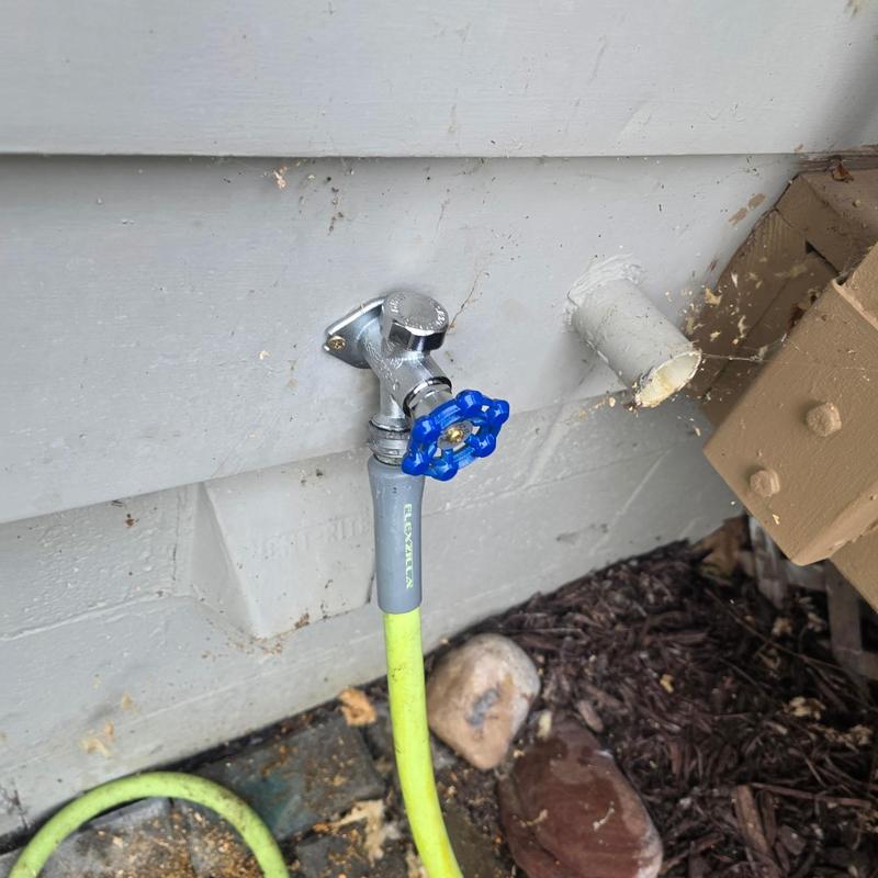 Hose bib with blue valve and attached garden hose