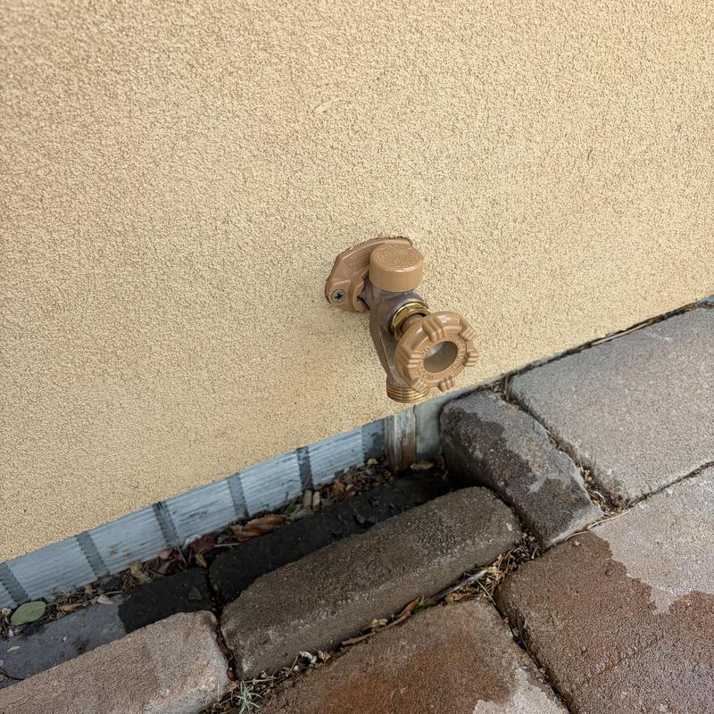 Outdoor hose bib on stucco wall with brick pavers Outdoor hose bib on stucco wall with brick pavers