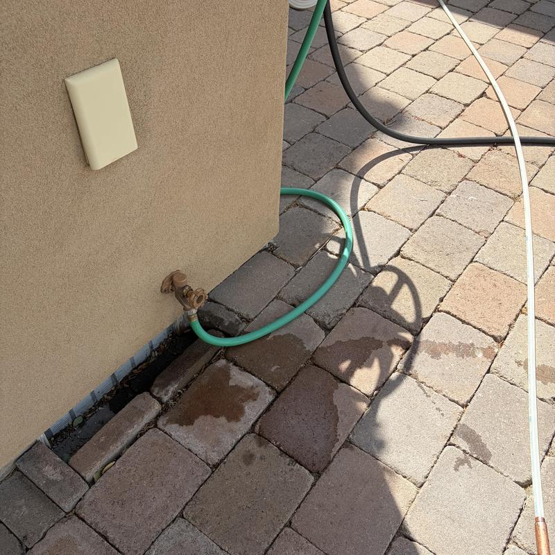 Hose bib with attached green garden hose on brick patio Hose bib with attached green garden hose on brick patio