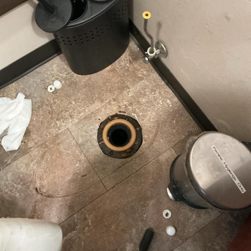 Toilet flange and plumbing setup in commercial restroom Toilet flange and plumbing setup in commercial restroom