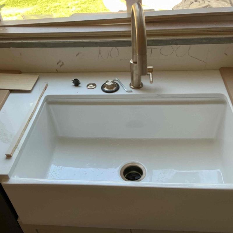 Kitchen faucet and white sink installation in progress