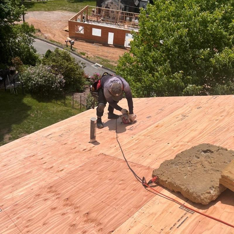 Roof plywood installation with worker using power tool