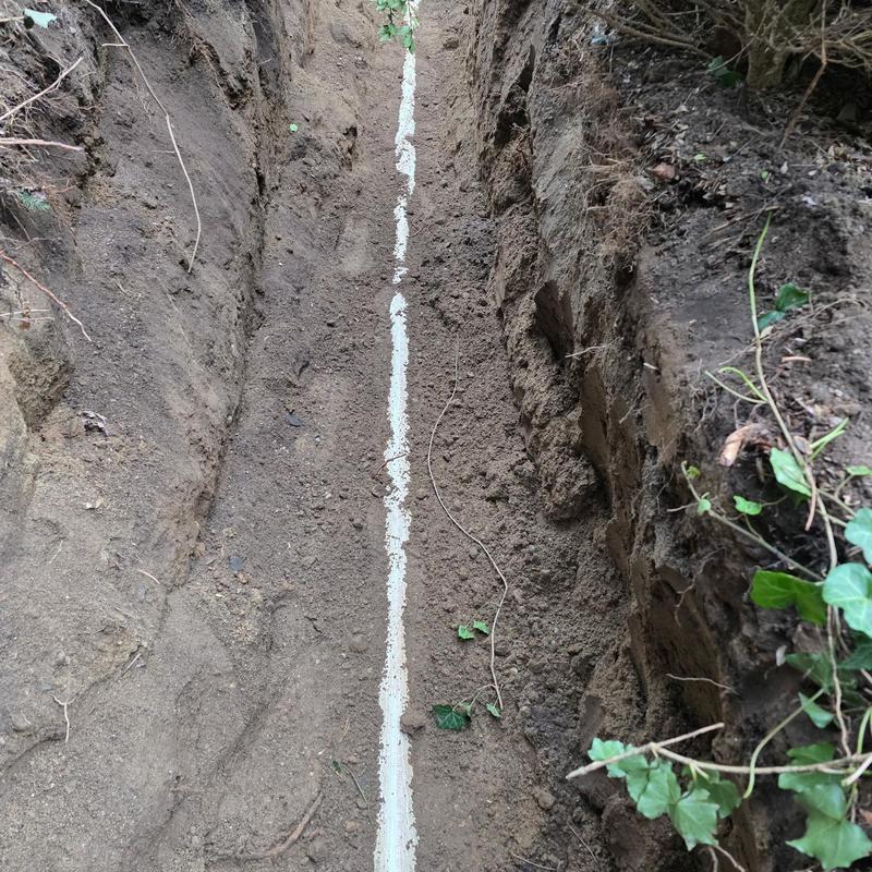 Septic pipe line dug trench with soil and plants nearby
