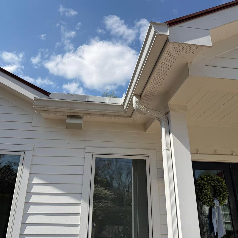 Gutter and downspout with damaged section near roof edge