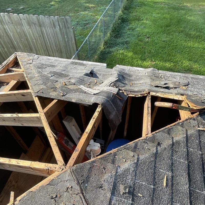 Shed roof with damaged shingles and exposed framing