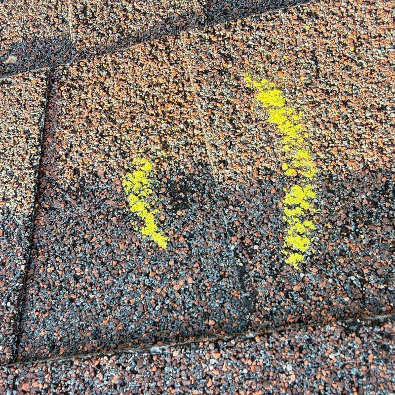 Roof shingles with yellow-marked hail damage spots