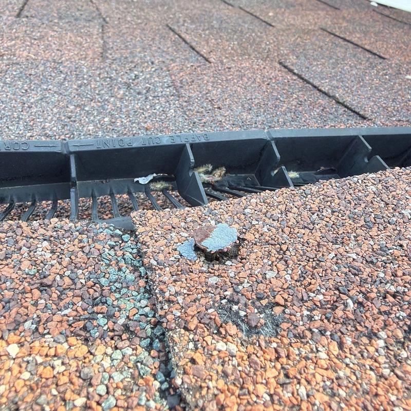 Asphalt shingle with hail impact damage near ridge vent