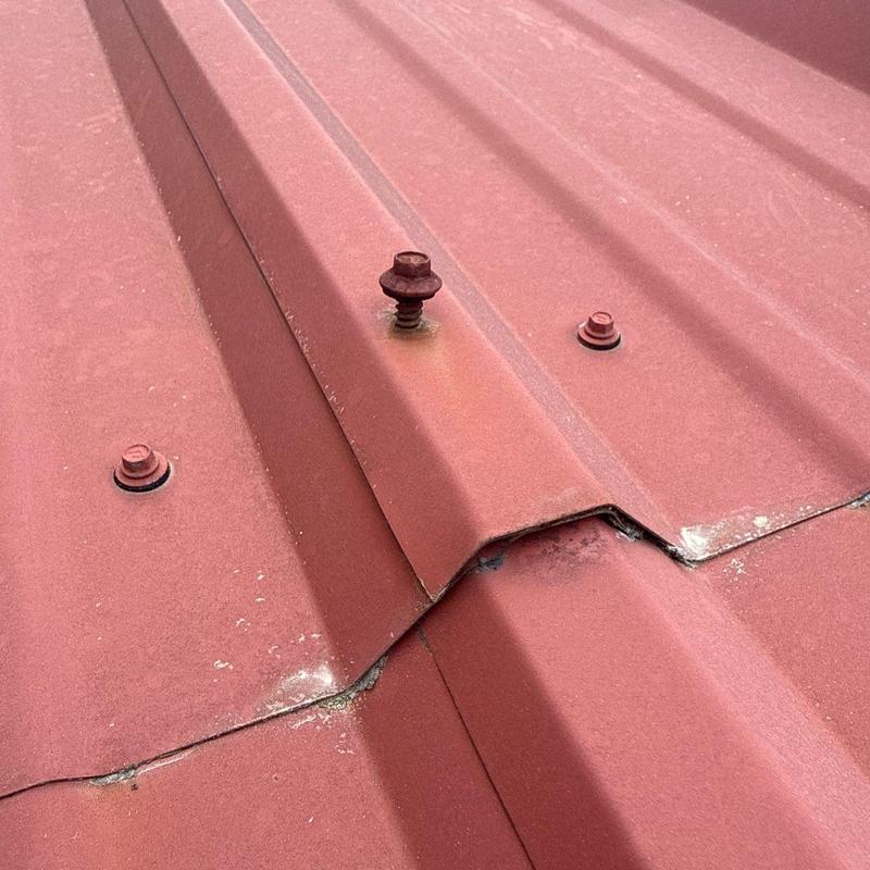 Metal roof seam with damaged and rusted fasteners