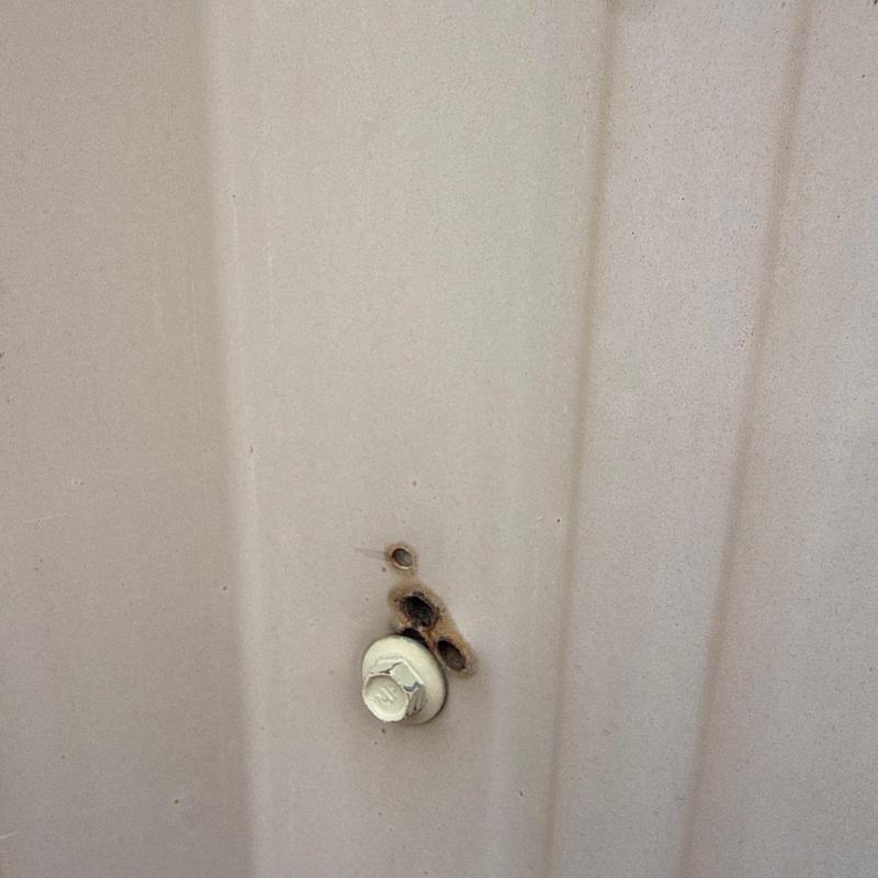Metal roof panel with rust and bolt corrosion damage